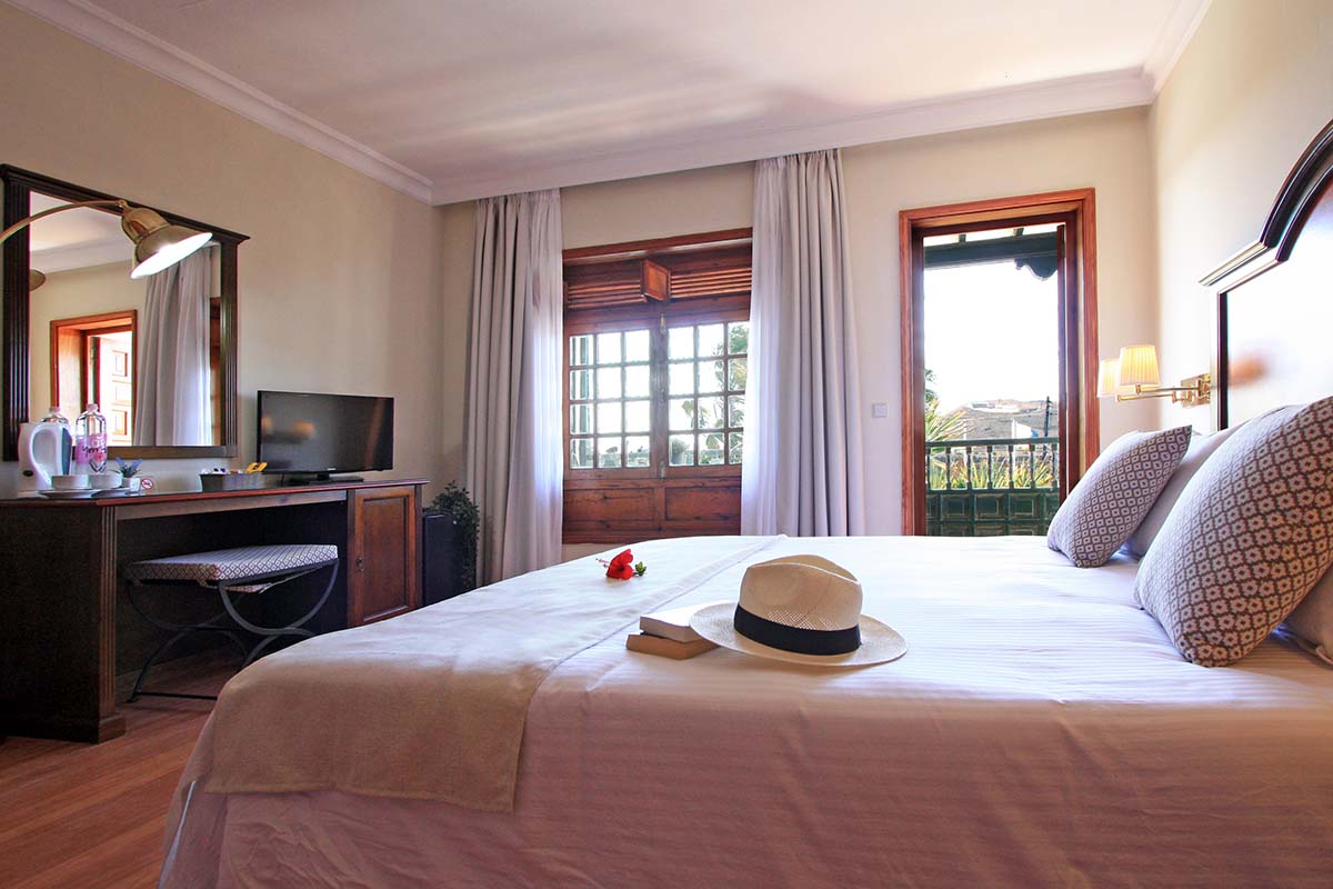 Chambre double lumineuse avec porte donnant sur la terrasse, équipée d'un grand lit, d'un bureau, d'une télévision et d'un minibar.
