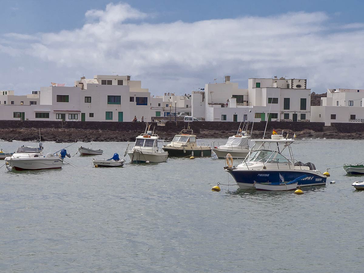 Puerto de Órzola con barcos pesqueros y bonitas casas blancas al fondo
