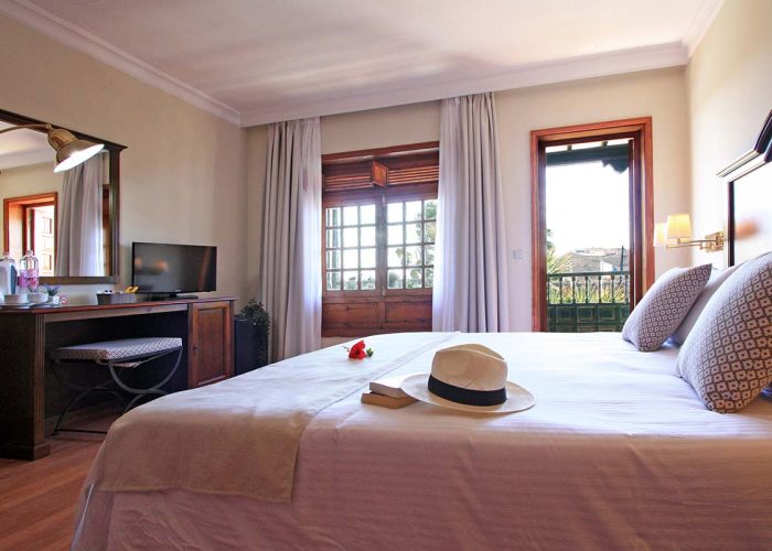 Chambre double lumineuse avec porte donnant sur la terrasse, équipée d'un grand lit, d'un bureau, d'une télévision et d'un minibar.